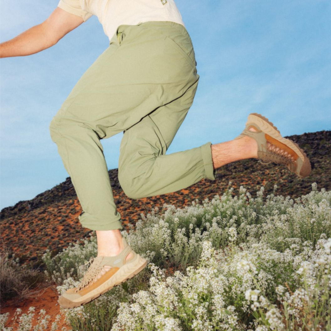 A man in hiking pants and a t-shirt leaping in the desert.